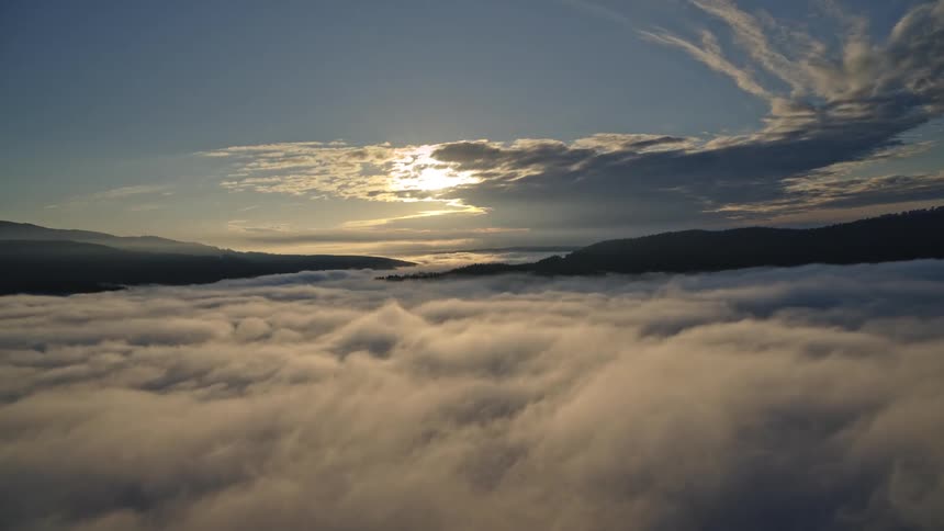 Aerial panorama of a mountain range on the horizon under clouds at sunrise