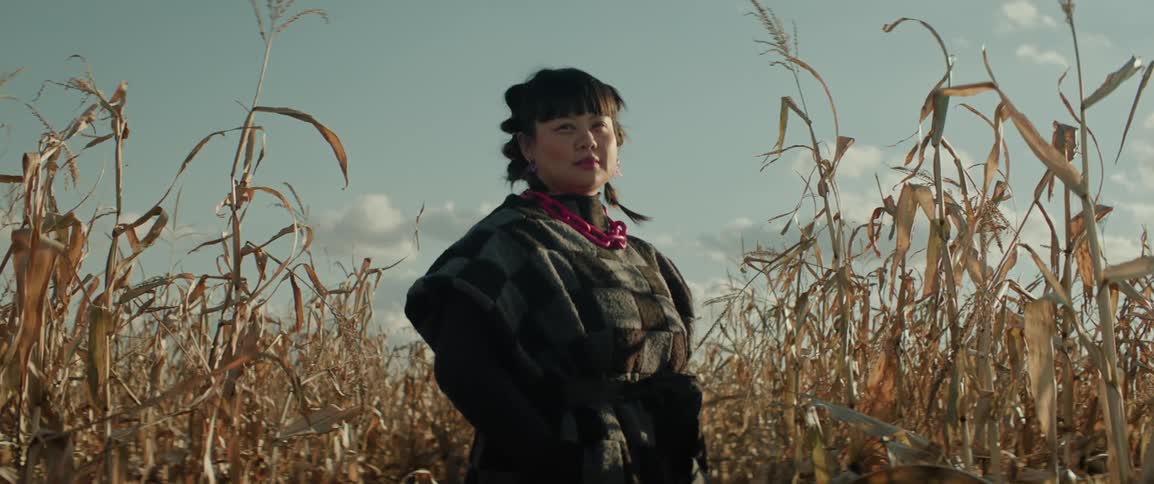Portrait of woman standing in a corn field in late afternoon