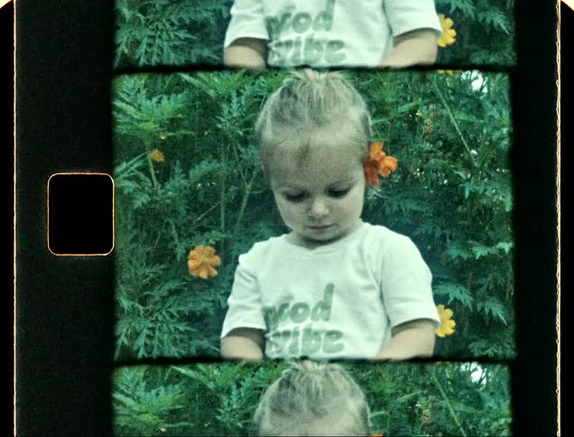 Portrait of a toddler in a garden smelling a yellow flower