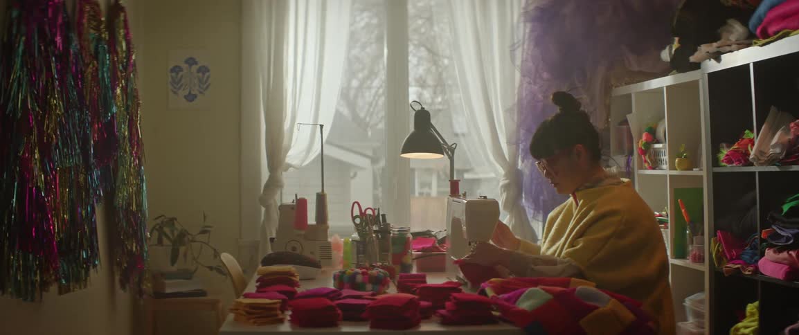 A woman sewing segments of clothing in a room