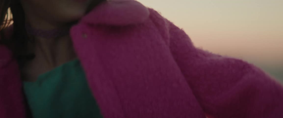 A young girl excitedly jumps up and down outside at sunset