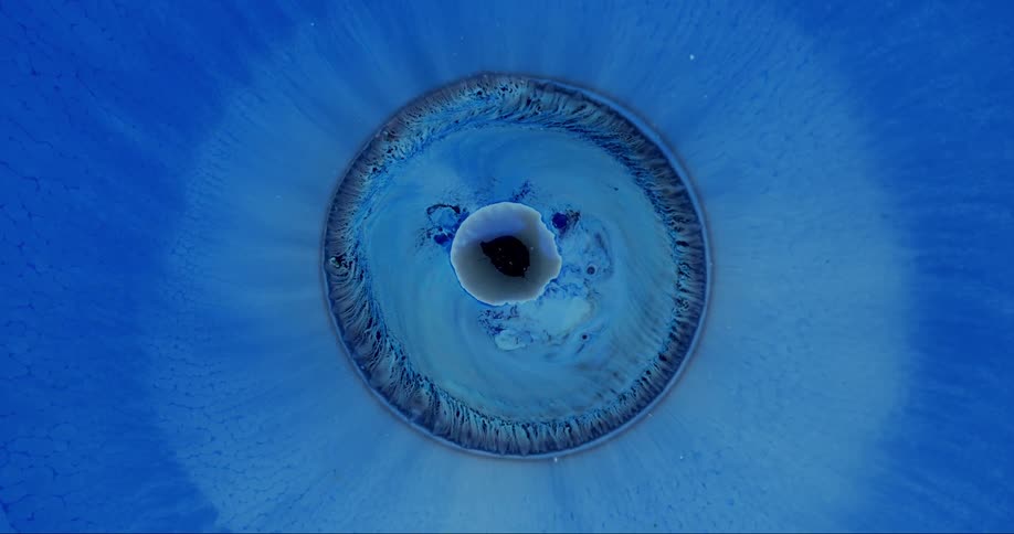 A blue circle withers up against a blue background with black center in abstract imagery
