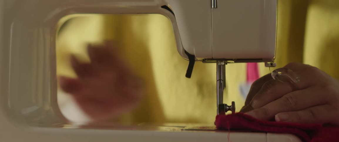 Closeup of a womans hands sewing fabric on a machine