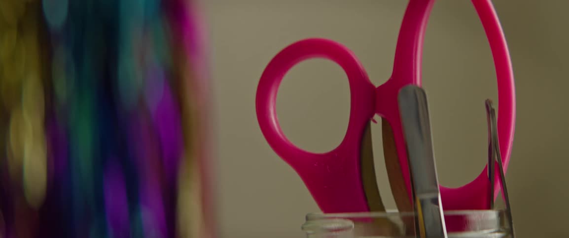 A woman picks of a pair of scissors from a cup and then returns them