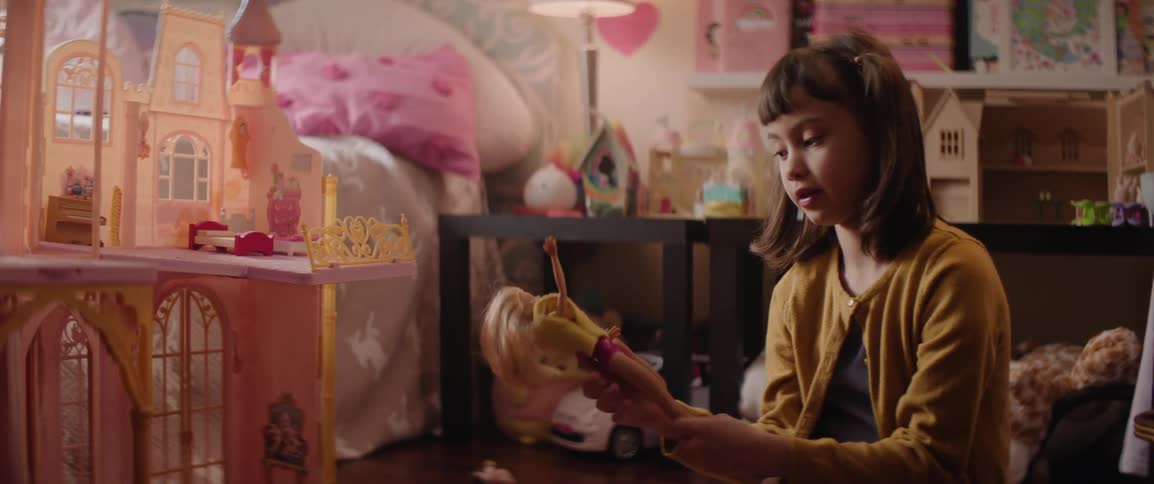 A young girl sitting on the floor of her room playing with dolls