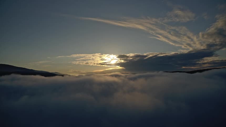 Aerial pushing through a thick layer of clouds at dawn