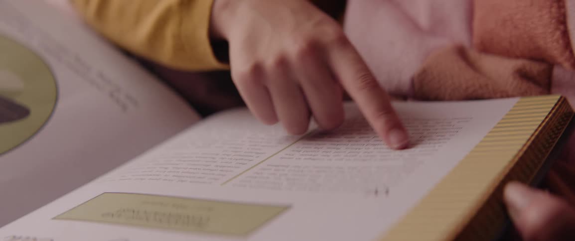 A child using her finger as a reading aid on a book