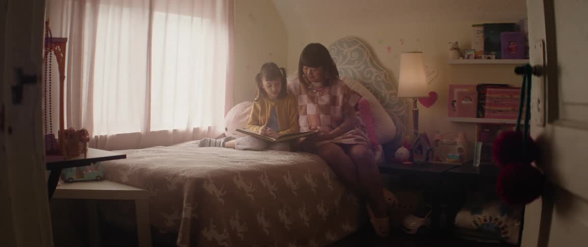 A mother and daughter read a book in bed