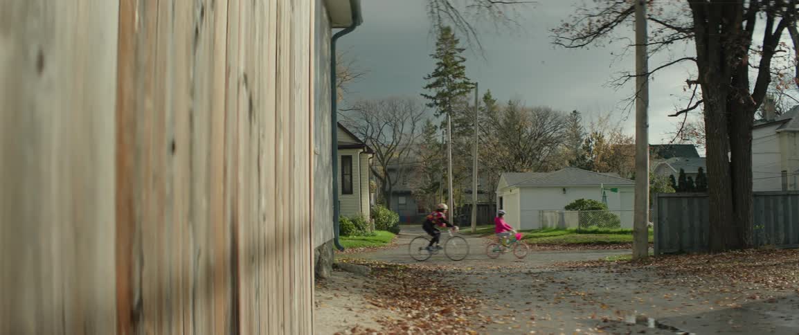 A woman and a young girl bicycling down a suburban road