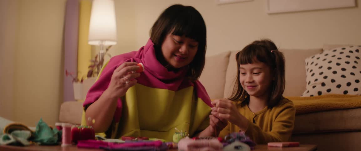 Mother and daughters sitting in their living room working with spools of thread