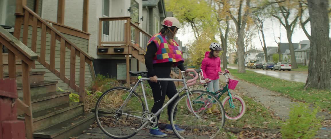 Mother walking down stairs with a bicycle alongside her daughter