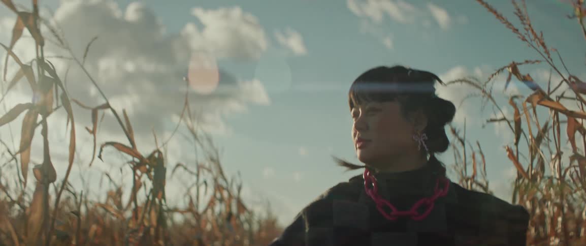 A woman walking through a field of corn during the day