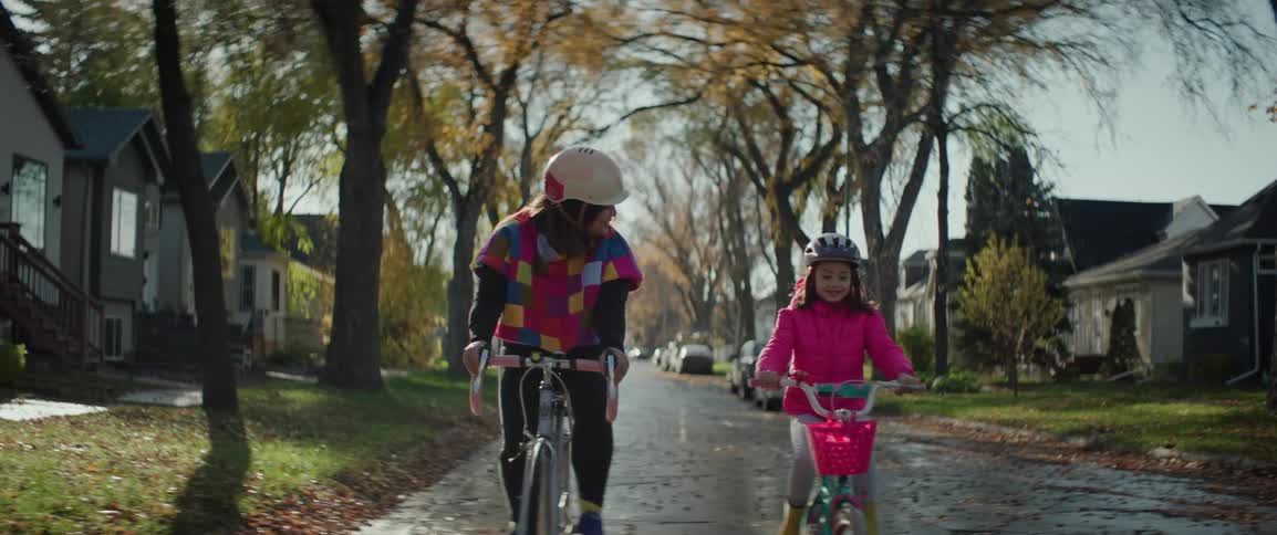 Mother and young girl riding bicycles on a suburban street in the sun