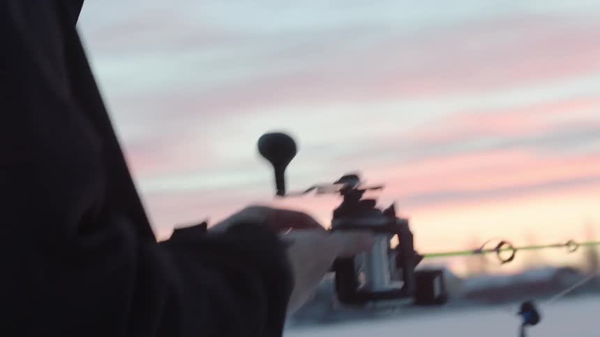 Man adjusting his fishing gear on a cold day at sunset