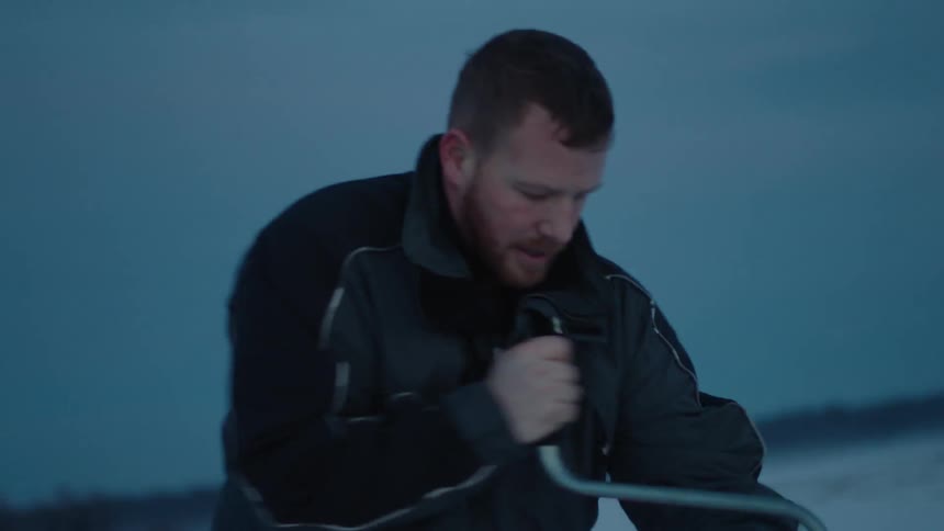 A man using an ice auger to bore a hole in a frozen lake