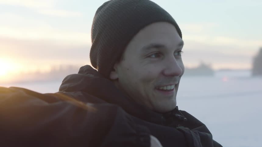 A man in a beanie laughs and looks away