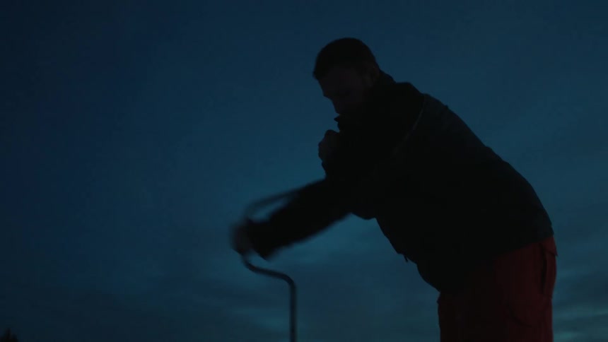 A man uses an ice auger on a frozen lake