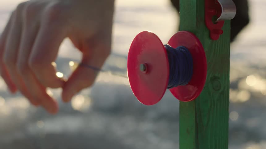 A person unwinds a spindle pulling string
