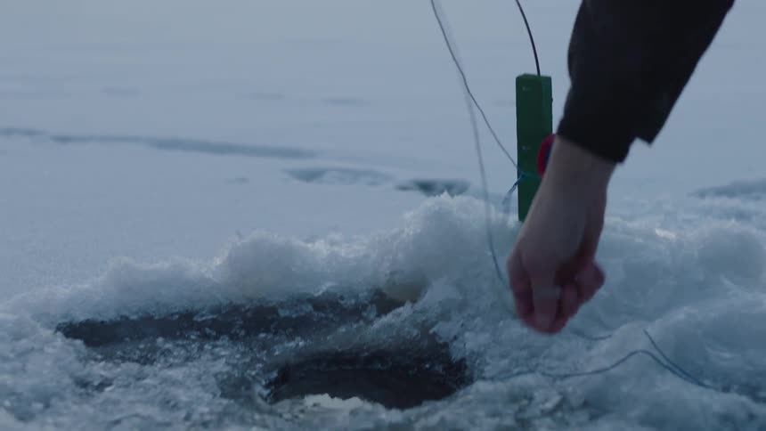 An ice fisherman checks his line