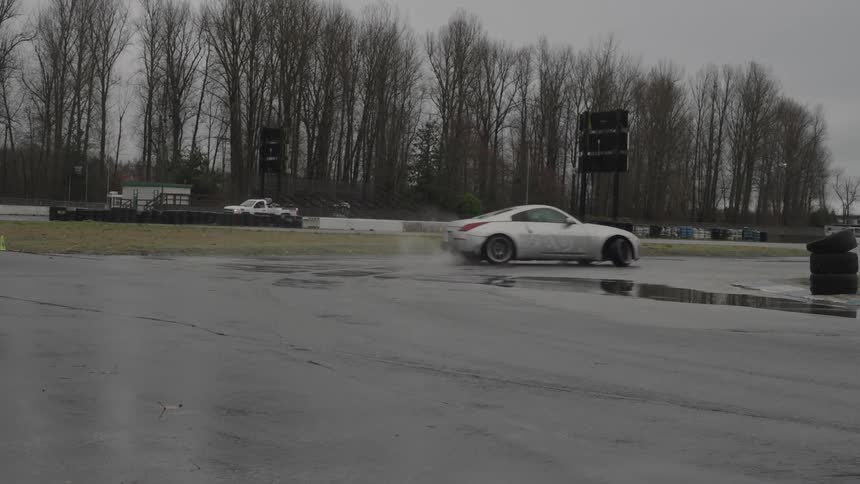 Sports car skids through puddle on race track on misty day