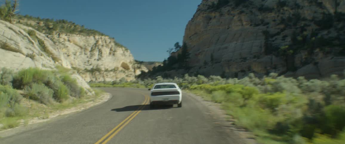 White sports car drives through a mountain pass