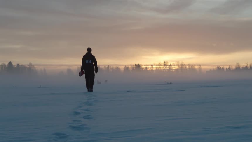 A man is walking across a snowy field