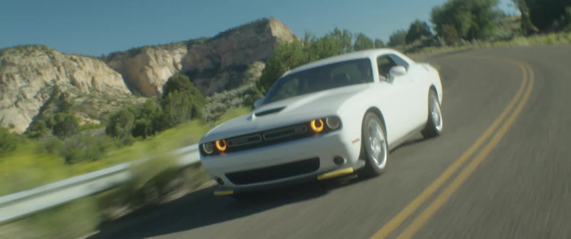 White sports car drives along highway passing mountain
