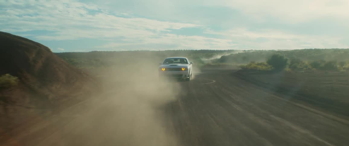 Whie car kick dust driving on a dirt road