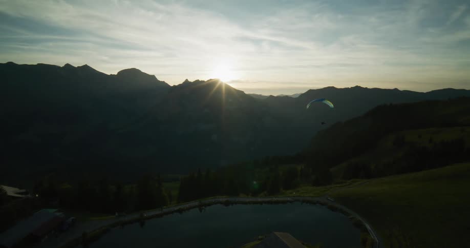 Aerial view of a paraglider over the mountains at sunset