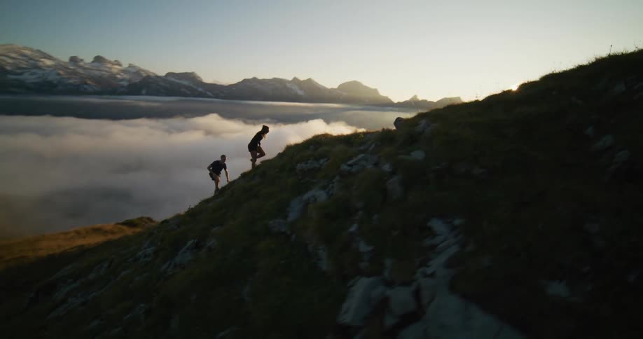 A couple of hikers climbing a mountain at sunset