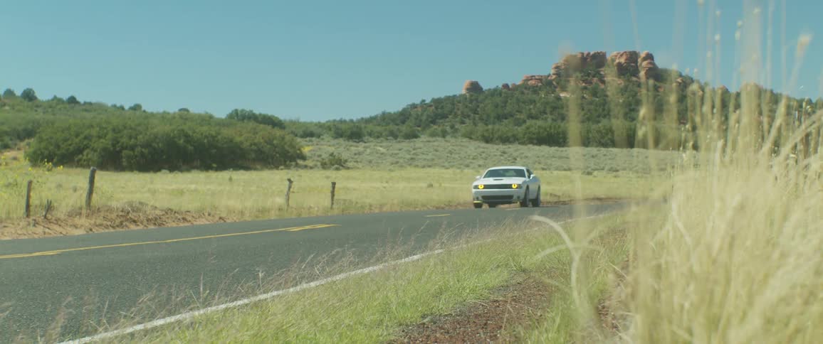 A white car driving on an asphalt road in a rural region