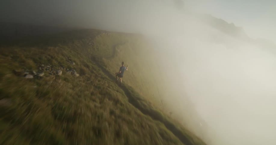 Two people running on top of a foggy hill
