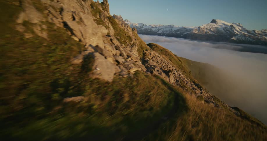 Man and woman running downhill on a mountain above a sea of clouds