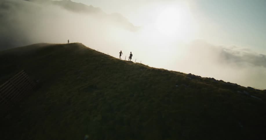 Two people running on a hill with rocks on top
