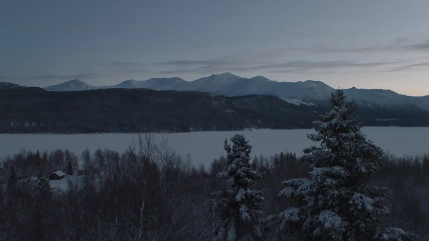 Small village covered in snow near lake and mountains