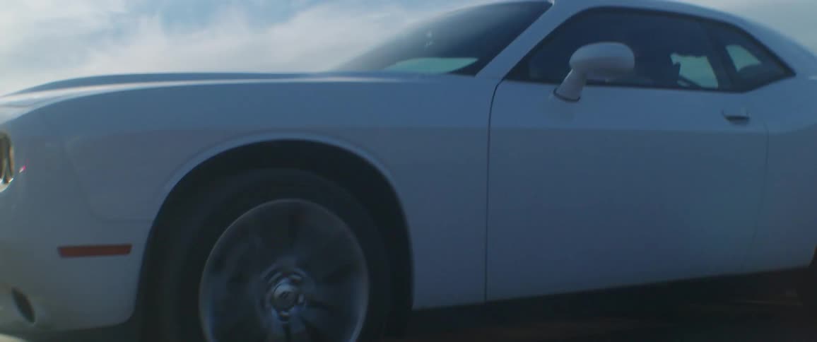 Closeup of a white camaro speeding on a dirt road