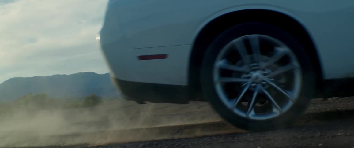 White sports car drives on a dirt road in the countryside