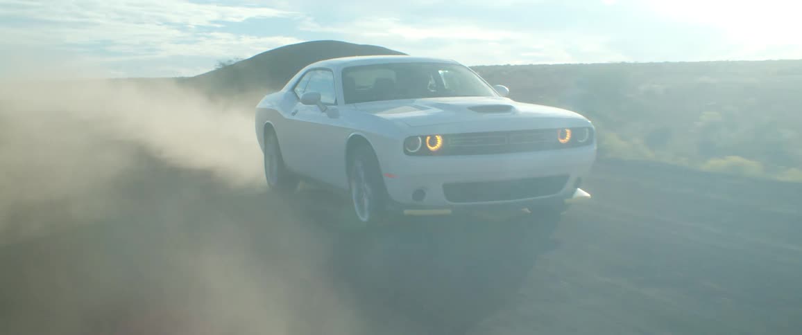 A car leaves a dust cloud behind on the dirt road