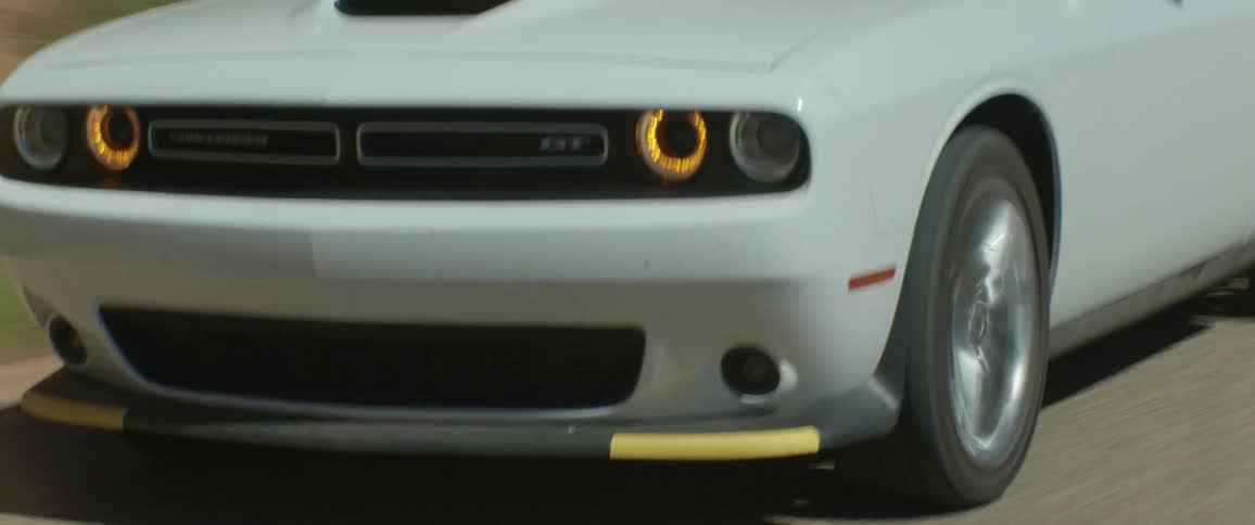 Man driving a white sports car on a desert highway on a sunny day