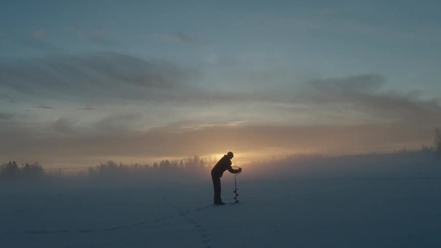 A person uses a hand auger to drill a hole in the ice
