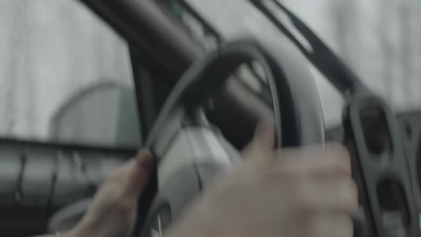 A human hand turning a steering wheel quickly and pulling a lever