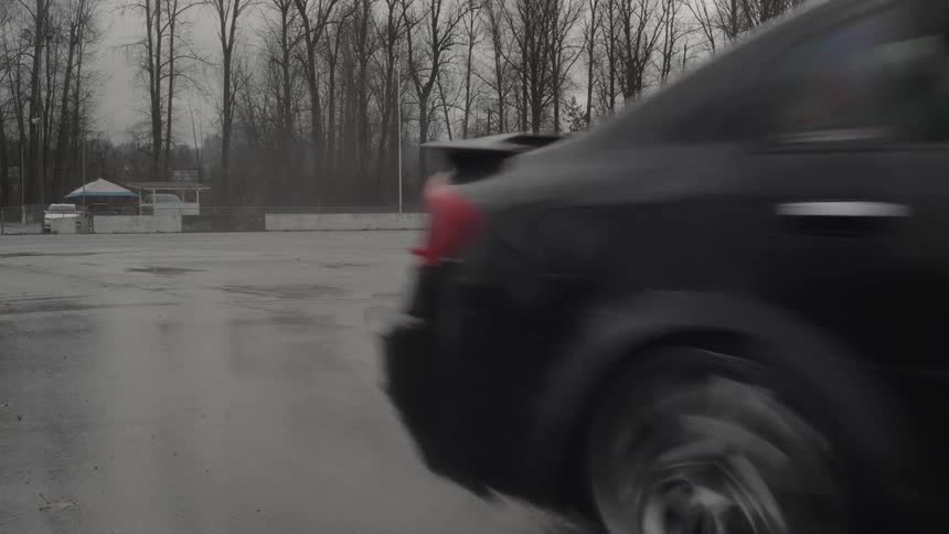 Two black cars skillfully drifting on wet ground
