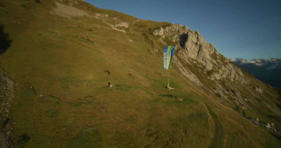 A person paragliding in the countryside around a lone building