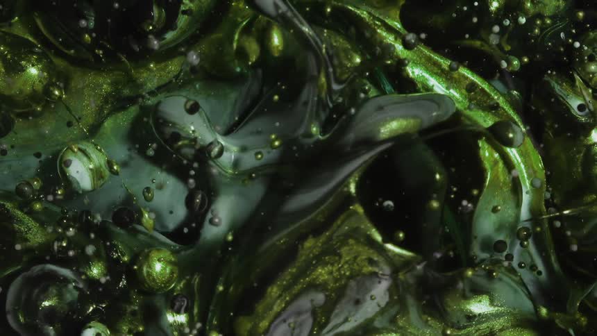 Abstract fluid art of flowing green metallic ink underwater