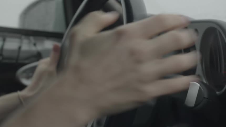 A human hand turns a steering wheel quickly and pulls a lever that is next to the