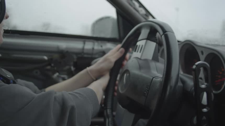 Female driver wearing helmet steers through a sharp turn on a foggy day
