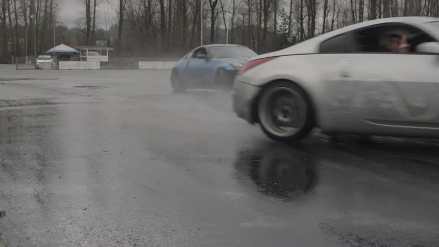 Two sports cars drifting on a wet track