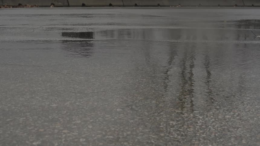 A puddle in the middle of a road splashes when tires run over it