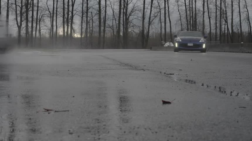 Two cars doing drift maneuvers on an asphalt surface with puddles of water