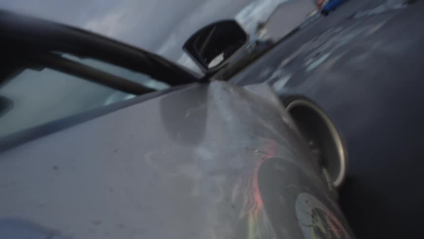 A car races around a track in circles with another car splashing through puddles on wet track